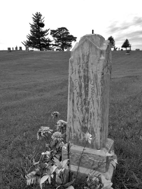 The grave of Paul Kuss in Otisco Cemetery, Minnesota. The tiny gravestones in the background are in the main cemetery. Paul Kuss committed suicide in 1910 and thus is buried in unconsecrated ground. Someone still cares, though--note the flowers.